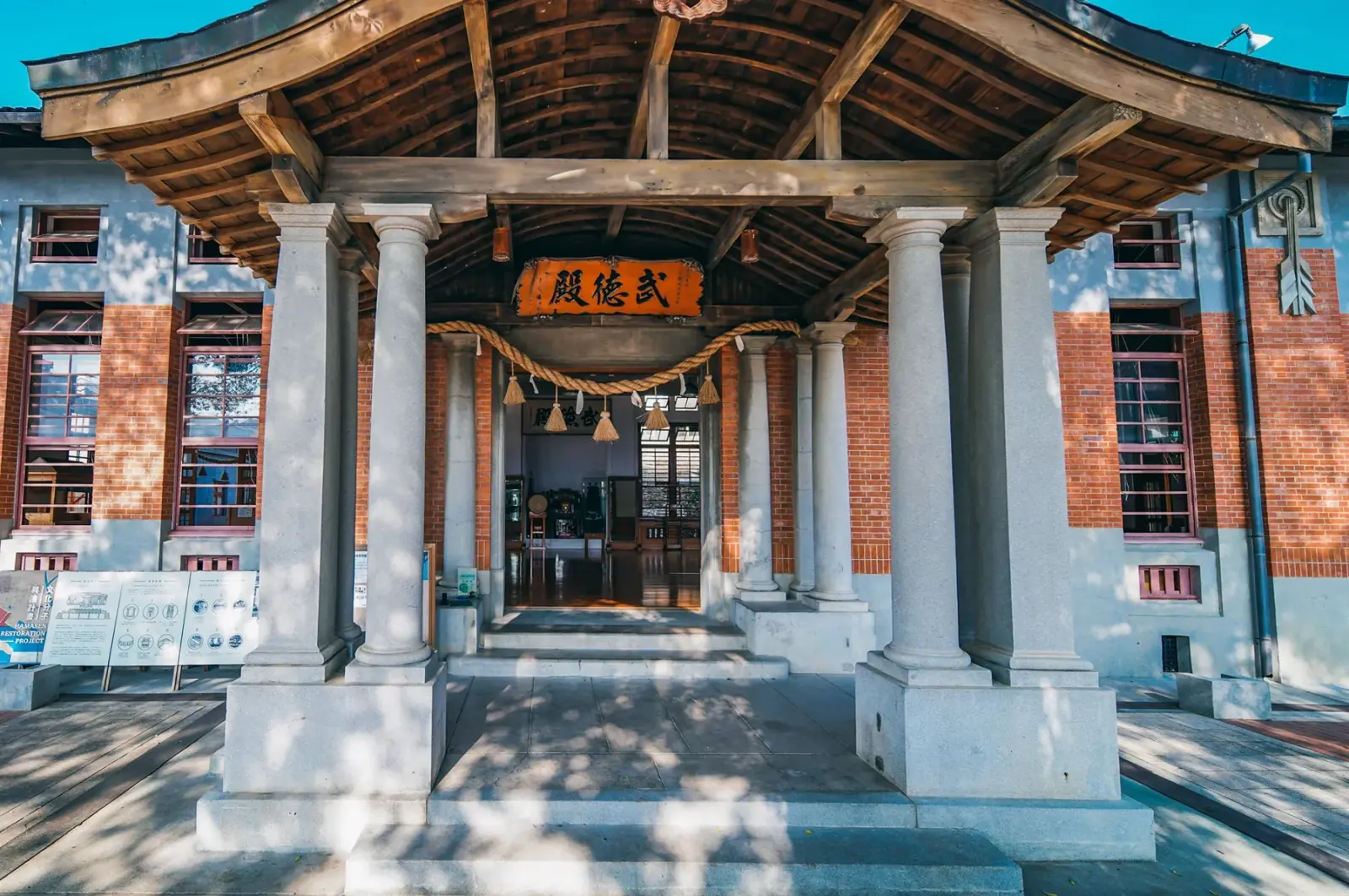 高雄武德殿正面入口，唐破風屋簷下懸掛「武德殿」朱紅匾額與注連繩，前方為灰色洗石子列柱。